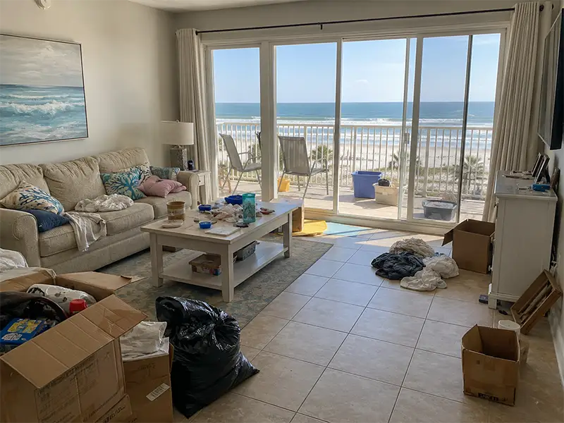 Beachfront condo in Pensacola Florida before cleanout with clutter, boxes, trash bags, and a messy living room left by renters